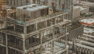 Construction site on a high-rise under development: exposed concrete floors, steel rebar, and scaffolding across multiple levels with a cityscape in the background | Beachy Construction